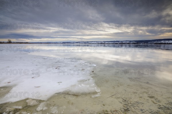 Sea of ice on the lakeshore with bright sky and snowy landscape in the background, campsite, Hegne,