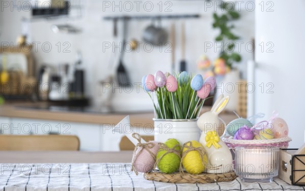 Easter decoration of colorful eggs in a basket and a rabbit on the kitchen table in a rustic style.