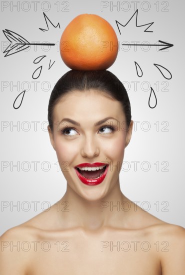 Creative portrait of a beautiful smiling woman holding a red grapefruit pierced with a sketchy
