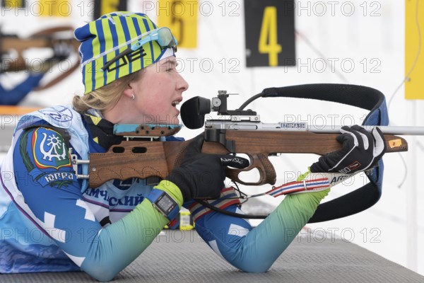 Sportswoman biathlete Legostaeva Anastasia rifle shooting in prone position. Biathlete in shooting