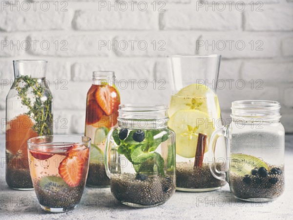 Different chia water in glass on gray background. Chia infused detox water with berries, fruits and