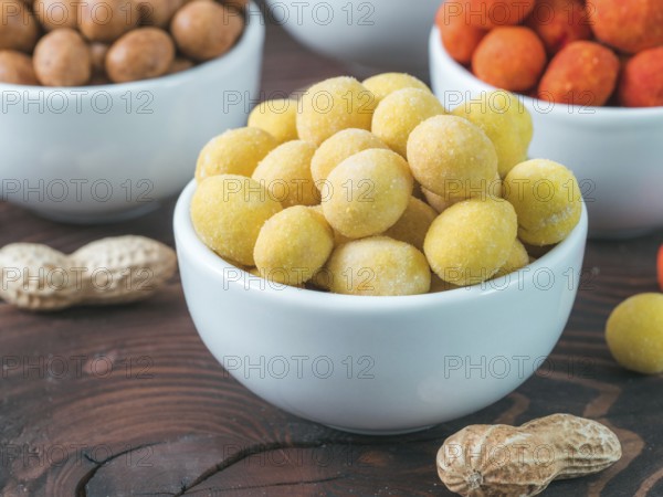 Peanut snack for beer, wine, party bar. Salted peanuts in yellow cheese glaze on brown wooden table