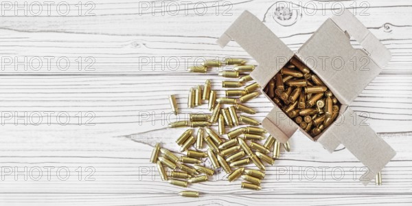 Top down view, carton box with yellow brass ammunition bullets on white wooden desk, banner - space