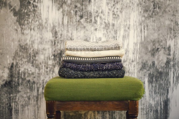 Pile of knitted warm grey and white blankets, scarves and woolen sweaters for winter or fall cold
