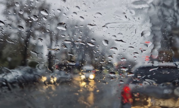 Melted snow and rain drops on the windshield of a car. Blurred outdoor view, winter season sleet as