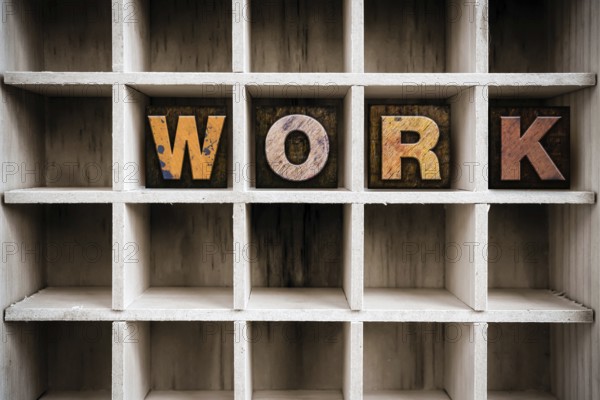The word WORK written in vintage ink stained wooden letterpress type in a partitioned printer's