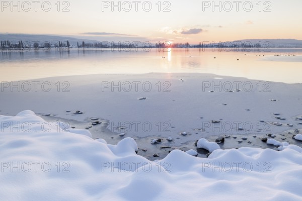 Snow-covered shores of a frozen lake at sunset, quiet and peaceful atmosphere, Seegarten,