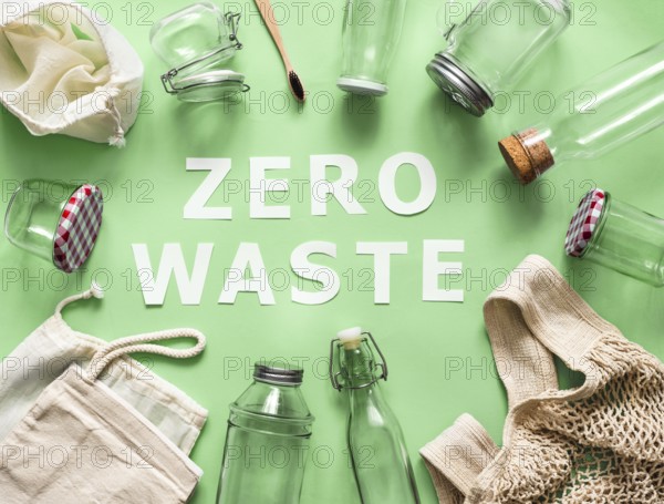Zero waste concept. Textile eco bags, glass jars and bamboo toothbrush on green background with