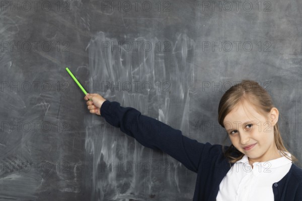 Schoolgirl shows on an empty school board. He is standing in the classroom at the chalkboard.
