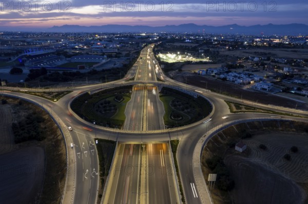 Aerial drone top view of a modern motorway junction roundabout with cars moving fast.