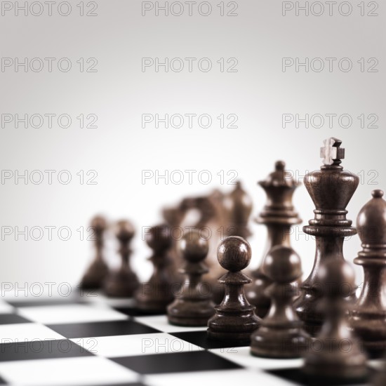 Strategy and tactics concept, black wooden chess figures on the board standing in a row ready for