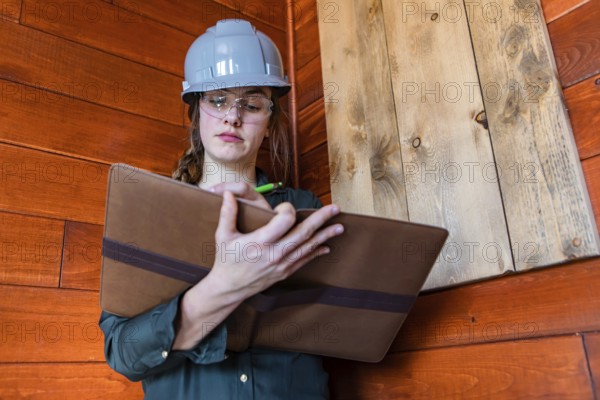 Construction female inspector using a clipboard to taking notes. a young caucasian woman worker
