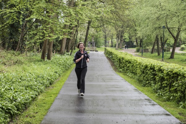 Jette, Brussels Capital Region Belgium, 04 24 2020 Attractive thirty year old woman jogging through