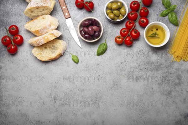 Food composition with sliced ciabatta, olives, olive oil, spaghetti, fresh basil, cherry tomatoes
