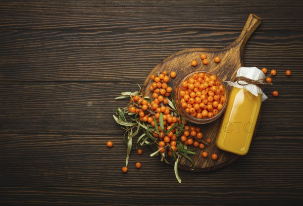 Sea buckthorn healthy drink in bottle, ripe berries in glass jar and branches with leaves top view