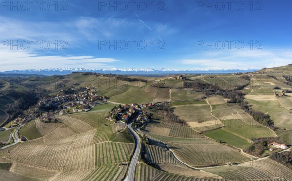 The hilly countryside in the Italian Piedmont with the village of Barolo and snow-covered mountains