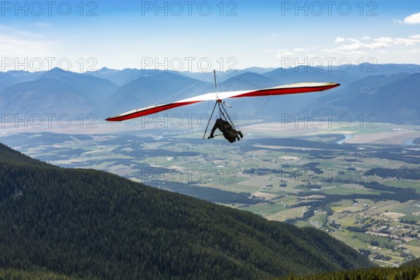 Long shot of flying extremal hang glider. Young man enjoying his recreational journey to Creston,