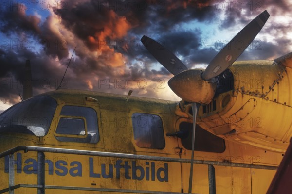 Old yellow aeroplane with propeller and a dramatic cloudy sky at sunset, Aero Commander 680E