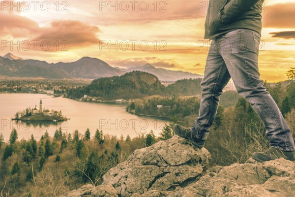 Man equipped with hiking shoes climbed on rocks above the lake Bled from Slovenia, in a December