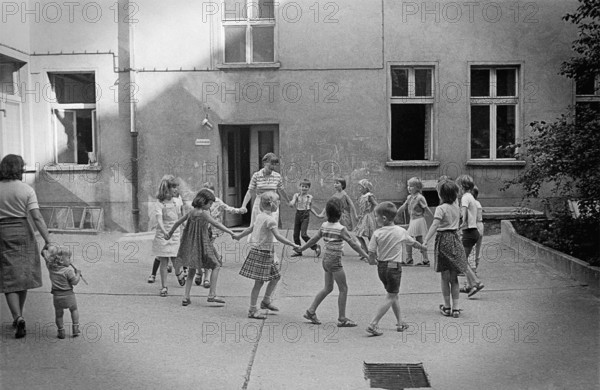 26/04/1983 GDR East Berlin district of Prenzlauer Berg. Children dancing in a circle with their