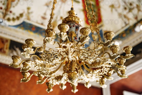 Close-up of an antique gold Italian chandelier. A chandelier-chandelier on gilded chains hangs