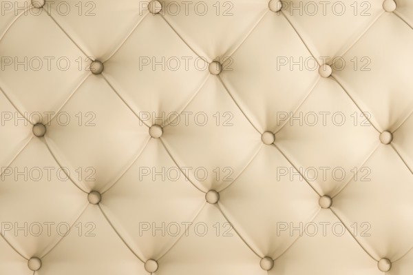 Beige soft tapestry pattern background with symmetrical buttons on the corners of diamonds. Soft