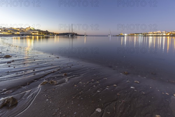 Night shot of a sandy beach and harbour at low tide. Panoramic image of an illuminated historic