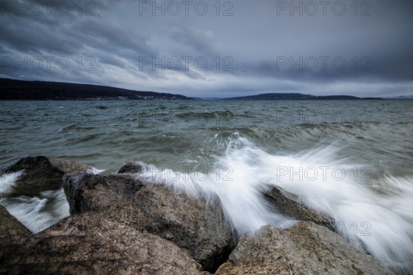 Sprayed waves crash against stones in front of a cloudy sky, harbour, Mittelzell, Reichenau, Lake