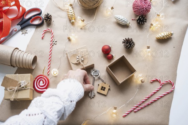 Key to house with keychain on cozy home in gift box with Christmas decor packaging. Pack present