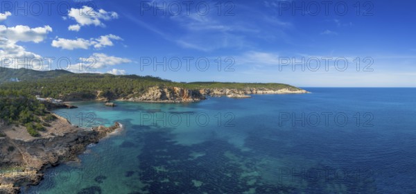 Aerial view the green and rugged hilly coast of northern Ibiza with the turquoise waters of Cala
