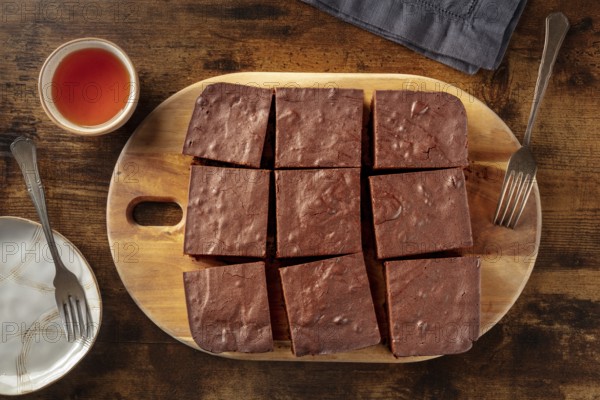 Chocolate brownie with tea, simple coffee cake, overhead flat lay view on a dark rustic wooden