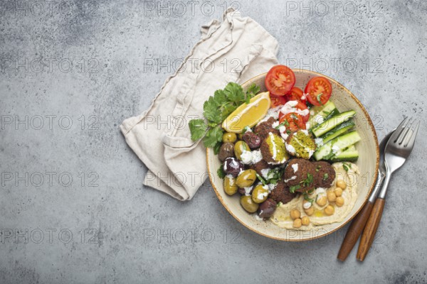 Falafel salad bowl with hummus, vegetables, olives, herbs and yogurt sauce. Vegan lunch plate top
