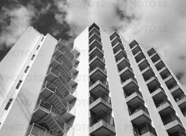 Monochrome angled detail view of an old 1960s white concrete apartment building with steps and