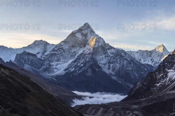 Ama Dablam mountain at sunrise and blue sky. Sun illuminates slopes. Himalayan mountains, Nepal,