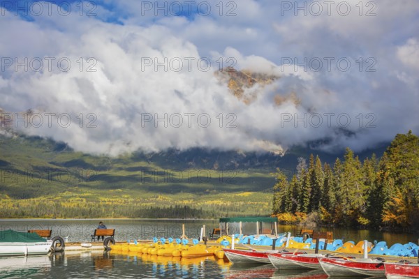 The wooden boat mooring with the moored boats. On the mooring there is elderly woman with camera.