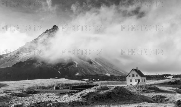 Black and white image of a Typical Icelandic winter landscape with a white small beautiful house