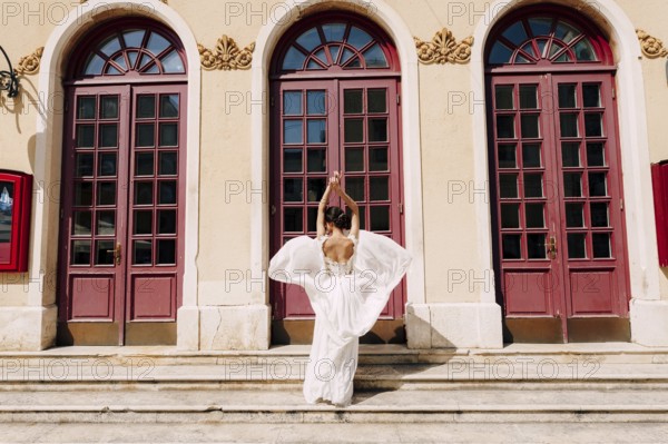 Sibenik, Croatia - 05.06.17: Bride in a white dress fluttering in the wind stands in front of high