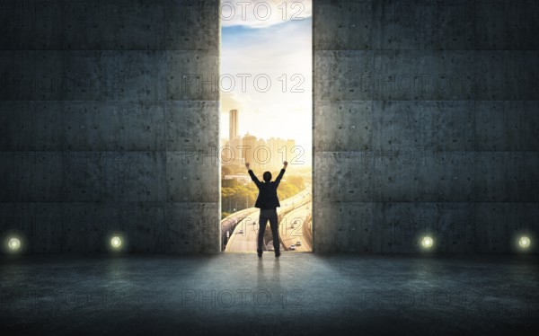 Success businessman cheering against concrete wall with huge door, sunrise scene city skyline