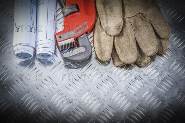Pipe wrench construction plans leather safety gloves on corrugated metal background building