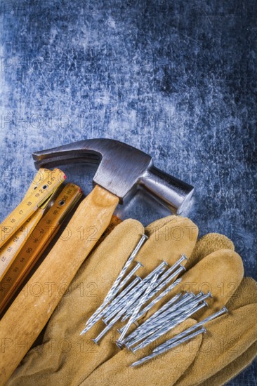 Leather safety working gloves set of construction nails wooden meter and claw hammer on scratched