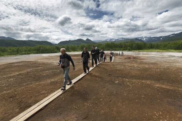 NALYCHEVO, KAMCHATKA, RUSSIA, JULY 30, 2014: Tourists walk on wooden deck, overlooking Thermal Pad