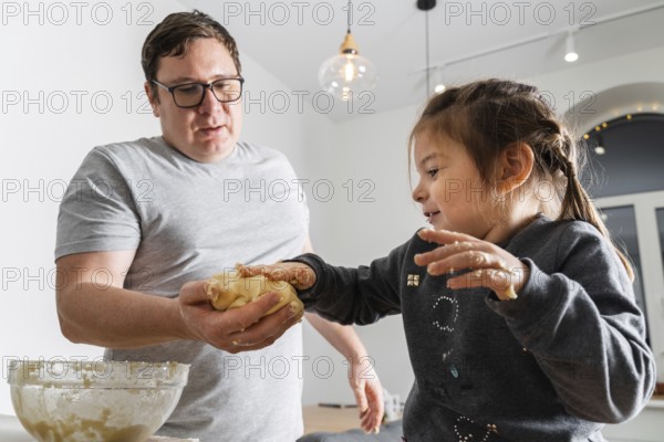 Father feeling playful with his caucasian little daughter, while preparing homemade dough for tasty