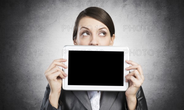 Businesswoman holding tablet computer with blank screen. Beautiful woman in business suit show