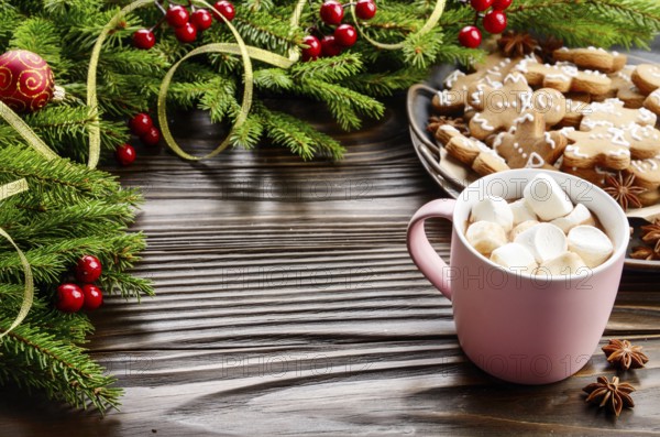 Christmas background of pink mug with hot chocolate and marshmallows, spruce branch and tray with