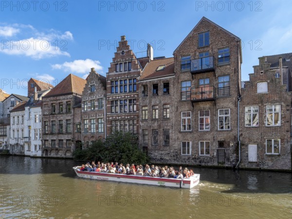 Tourists in the tourist boat for the canal cruise on the river Leie and in the background together