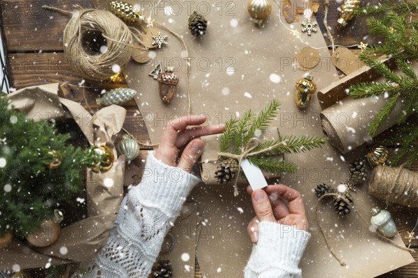 Hands pack a gift for Christmas and new year in eco-friendly materials: kraft paper, live fir