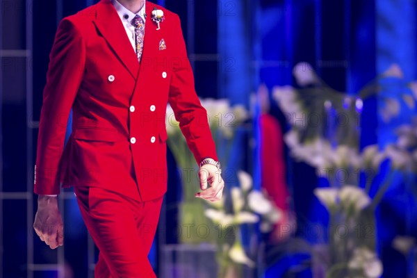 Male model walks the runway in red suit during a Fashion Show. Fashion catwalk event showing new
