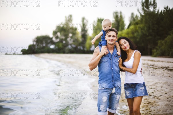Beautiful young family on holiday with baby. The father holds the blonde girl in her arms, and the