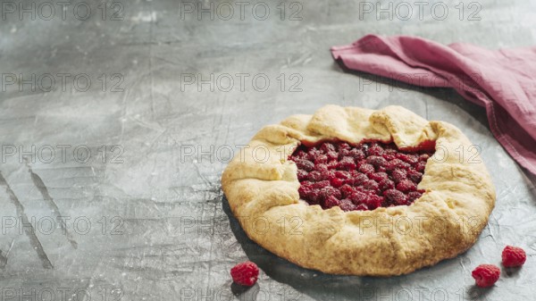 Perfect raspberry galette. Delicious rustic homemade tart with frozen or fresh raspberries on gray