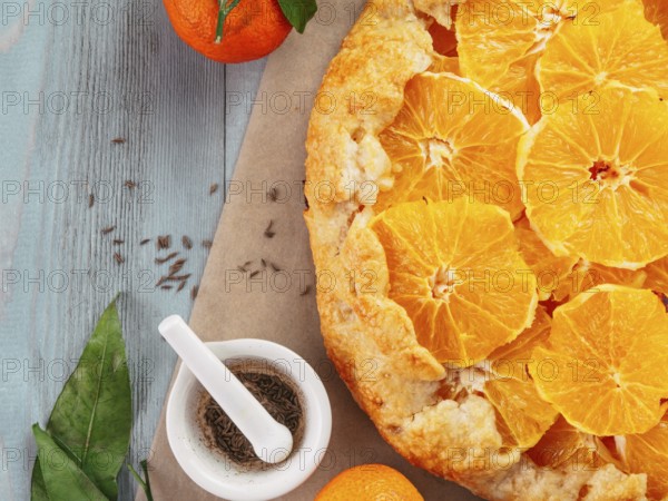 Top view of caraway and orange tart on baking paper over gray wooden table with copy space.Winter